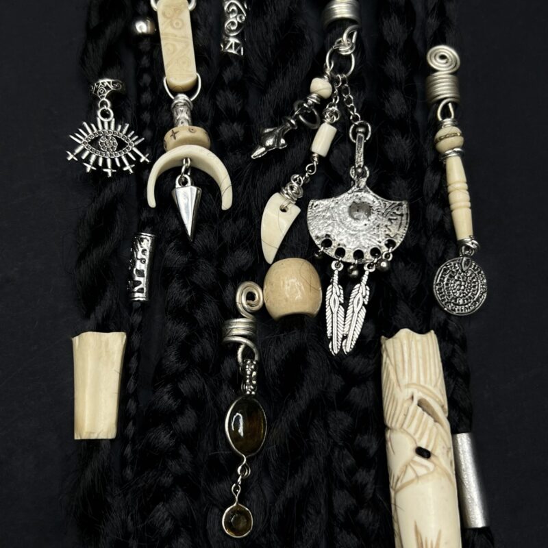 Handcrafted hair jewellery by ThreadXDreads featuring decorative charms, pendants, beads, and ornaments attached to black braids and dreadlocks