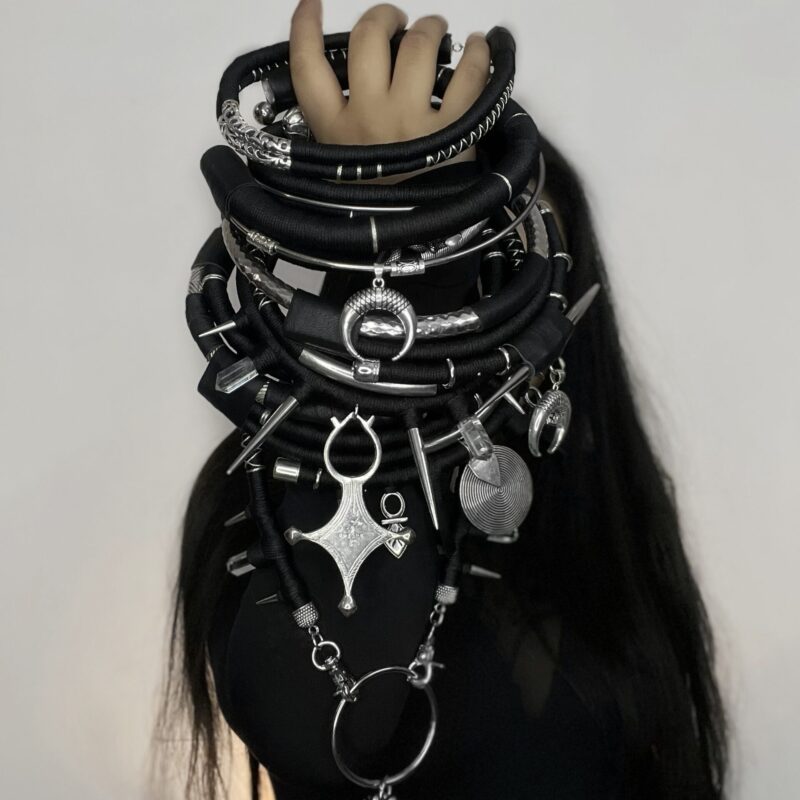 Handcrafted black statement neckpiece by ThreadXDreads featuring metallic charms, spikes, rings, pendants, and layered alternative fashion details